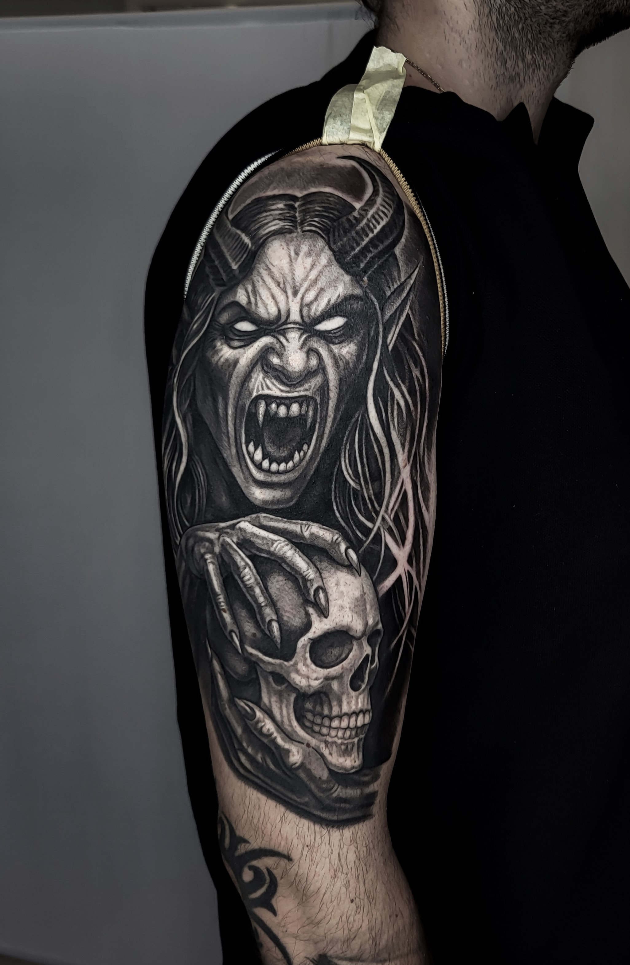 Black & grey tetovaža demonske ženske in lobanje na nadlakti