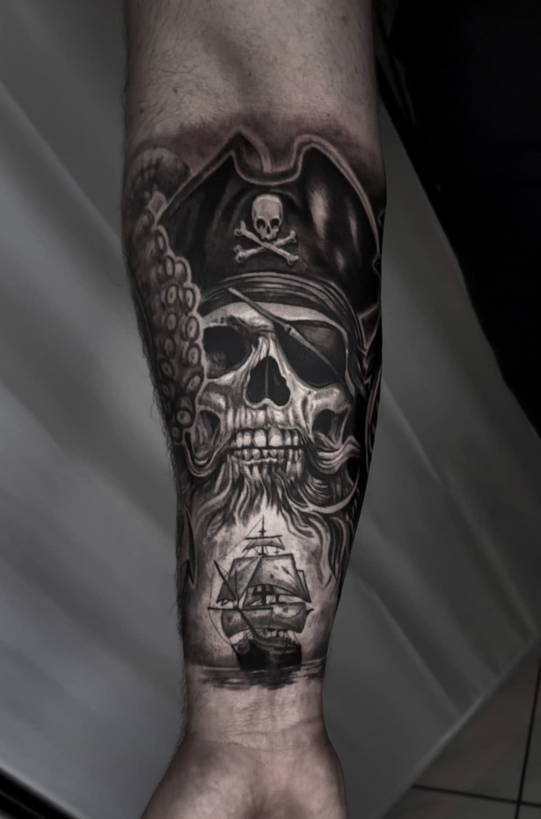 Black & grey tetovaža piratske lobanje in ladje na spodnjem delu noge